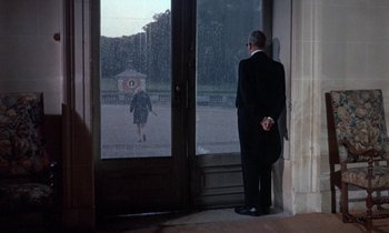 Movie still from “Belle de Jour” (1967), directed by Luis Buñuel – A man standing in front of an open front door; Wide shot, Over the shoulder angle