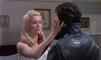 Movie still from “Belle de Jour” (1967), directed by Luis Buñuel – A woman in a white dress is touching a man in a leather jacket; Close Up shot, Over the shoulder angle