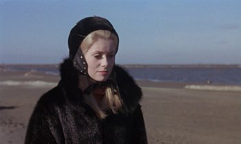Movie still from “Belle de Jour” (1967), directed by Luis Buñuel – A woman wearing a fur coat and a helmet on the beach; Close Up shot, Low angle