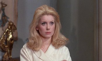 Movie still from “Belle de Jour” (1967), directed by Luis Buñuel – A woman in a white shirt is posing for a picture; Close Up shot, Over the shoulder angle