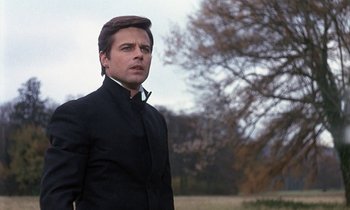 Movie still from “Belle de Jour” (1967), directed by Luis Buñuel – A man in a black jacket and a brown hat is standing in front of a tree; Close Up shot, Low angle