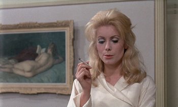 Movie still from “Belle de Jour” (1967), directed by Luis Buñuel – A woman smoking a cigarette in front of a painting; Close Up shot, Over the shoulder angle