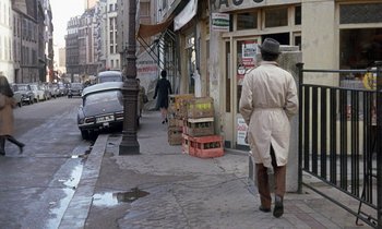 Movie still from “Belle de Jour” (1967), directed by Luis Buñuel – An old man walking down the street in the rain; Wide shot, High angle