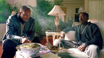 Two men sitting at a table with a bowl of food on the table