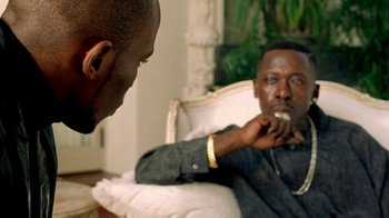 A man sitting in front of another man eating something
