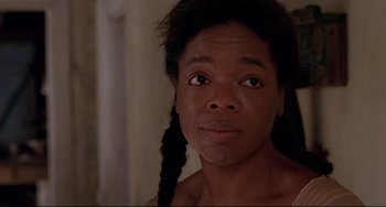 Movie still from “Beloved” (1998), directed by Jonathan Demme – A young woman with long braids looking into the camera; Close Up shot, Over the shoulder angle