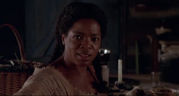 Movie still from “Beloved” (1998), directed by Jonathan Demme – An african american woman with a microphone in a dark room; Close Up shot, Over the shoulder angle