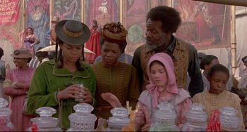 Movie still from “Beloved” (1998), directed by Jonathan Demme – A group of people standing around a table with candles; Medium shot, Over the shoulder angle