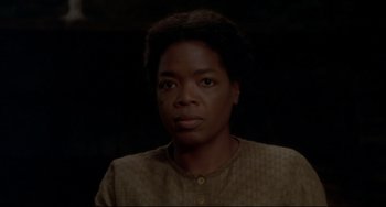 Movie still from “Beloved” (1998), directed by Jonathan Demme – A black woman with short black hair wearing a brown shirt; Close Up shot, Over the shoulder angle