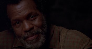 Movie still from “Beloved” (1998), directed by Jonathan Demme – An older man with grey hair and beard smiling; Close Up shot, Low angle