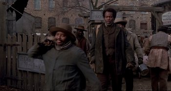 Movie still from “Beloved” (1998), directed by Jonathan Demme – A group of men standing next to each other on a street; Medium shot, Low angle