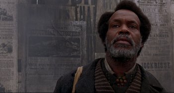 Movie still from “Beloved” (1998), directed by Jonathan Demme – An older man with a beard and a mustache is standing in front of a wall; Close Up shot, Low angle