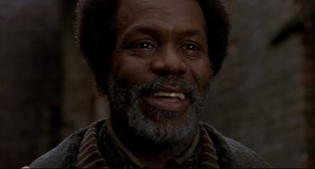 Movie still from “Beloved” (1998), directed by Jonathan Demme – An older man with grey hair and a beard smiling for the camera; Close Up shot, Low angle