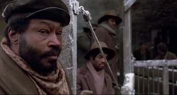 Movie still from “Beloved” (1998), directed by Jonathan Demme – A group of men standing next to each other on a street; Close Up shot, Low angle