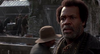 Movie still from “Beloved” (1998), directed by Jonathan Demme – An older man with a beard and a hat in the background; Close Up shot, Over the shoulder angle