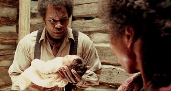 Movie still from “Beloved” (1998), directed by Jonathan Demme – A man holding a baby in front of two women; Close Up shot, Over the shoulder angle