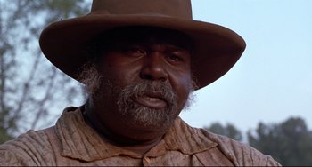 Movie still from “Beloved” (1998), directed by Jonathan Demme – An older man wearing a brown hat and a brown shirt; Close Up shot, Low angle