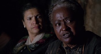 Movie still from “Beloved” (1998), directed by Jonathan Demme – Two older women looking at the camera in the dark; Close Up shot, Over the shoulder angle