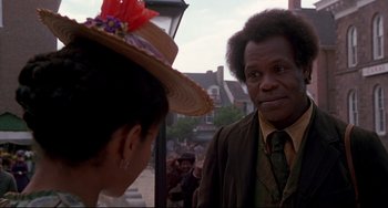 Movie still from “Beloved” (1998), directed by Jonathan Demme – A man and a woman are standing in front of a crowd; Close Up shot, Over the shoulder angle