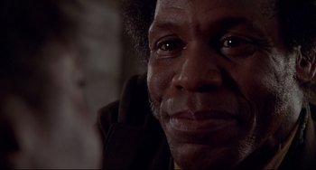 Movie still from “Beloved” (1998), directed by Jonathan Demme – An older man with a black shirt and brown jacket looking at the camera; Close Up shot, Low angle