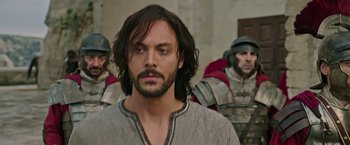 Movie still from “Ben-Hur” (2016), directed by Timur Bekmambetov – A person with a beard in front of some soldiers; Close Up shot, Over the shoulder angle