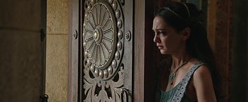 Movie still from “Ben-Hur” (2016), directed by Timur Bekmambetov – A woman standing in front of an ornate wooden door; Close Up shot, Over the shoulder angle