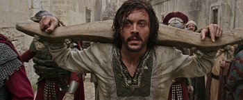 Movie still from “Ben-Hur” (2016), directed by Timur Bekmambetov – A man with long hair holding a wooden stick; Medium shot, Low angle