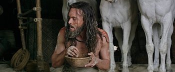 Movie still from “Ben-Hur” (2016), directed by Timur Bekmambetov – A man with long hair is holding a wooden bowl; Medium shot, Low angle