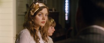 A young woman wearing a gold bow headband