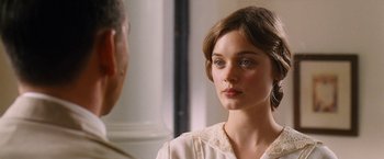 A woman in a white dress looking at a man in a white suit