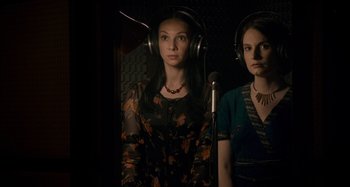 Two women are listening to music in a recording studio