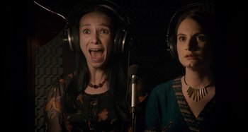 Two women are singing in a recording studio