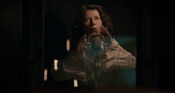 A woman is singing into a microphone in front of a microphone stand