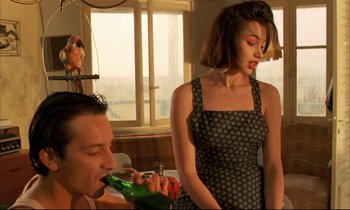 Movie still from “Betty Blue” (1986), directed by Jean-Jacques Beineix – A man and a woman are drinking a beer together; Medium shot, Low angle