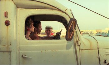 Movie still from “Betty Blue” (1986), directed by Jean-Jacques Beineix – A group of people sitting in the back of an old truck; Medium shot, Over the shoulder angle