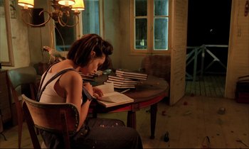Movie still from “Betty Blue” (1986), directed by Jean-Jacques Beineix – A woman sitting at a table reading a book; Medium shot, High angle