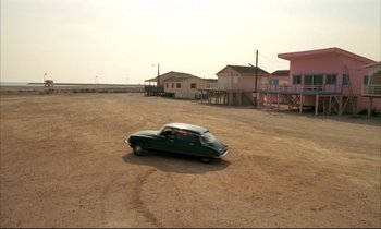 Movie still from “Betty Blue” (1986), directed by Jean-Jacques Beineix – An old car parked in the middle of a dirt field; Extreme Wide shot, High angle