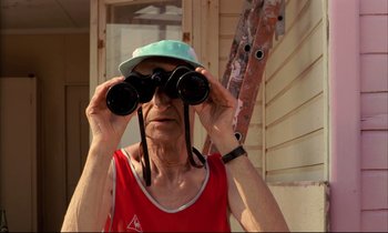 Movie still from “Betty Blue” (1986), directed by Jean-Jacques Beineix – An older man looking through a pair of binoculars; Medium shot, Low angle