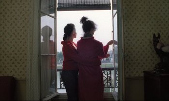 Movie still from “Betty Blue” (1986), directed by Jean-Jacques Beineix – Two young women are looking out of a window; Medium shot, Over the shoulder angle
