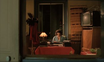 Movie still from “Betty Blue” (1986), directed by Jean-Jacques Beineix – A woman sitting at a table with a typewriter; Wide shot, High angle