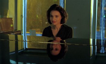 Movie still from “Betty Blue” (1986), directed by Jean-Jacques Beineix – A woman sitting in front of a glass table in a room; Close Up shot, Over the shoulder angle