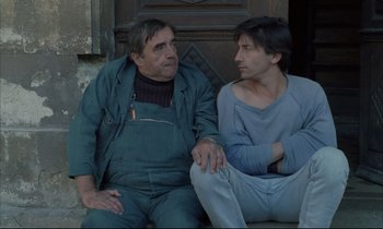Movie still from “Betty Blue” (1986), directed by Jean-Jacques Beineix – Two men sitting next to each other on a bench; Medium shot, Low angle