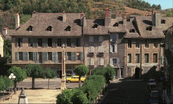 Movie still from “Betty Blue” (1986), directed by Jean-Jacques Beineix – A yellow car parked in front of a row of houses; Extreme Wide shot, High angle