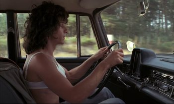 Movie still from “Betty Blue” (1986), directed by Jean-Jacques Beineix – A woman driving a car in the road; Medium shot, Low angle