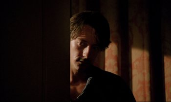 Movie still from “Betty Blue” (1986), directed by Jean-Jacques Beineix – A man standing next to a wall in the dark; Close Up shot, Over the shoulder angle