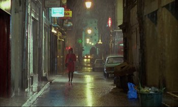 Movie still from “Betty Blue” (1986), directed by Jean-Jacques Beineix – A woman in a red raincoat walking down a wet street; Extreme Wide shot, High angle