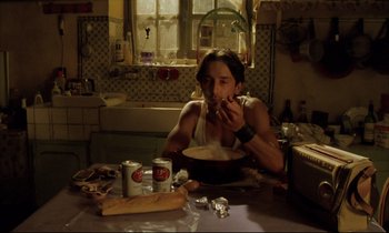 Movie still from “Betty Blue” (1986), directed by Jean-Jacques Beineix – A man sitting at a kitchen table eating a bowl of soup; Medium shot, High angle