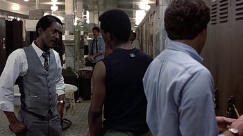 Movie still from “Beverly Hills Cop” (1984), directed by Martin Brest – A group of people standing in a hallway; Medium shot, Over the shoulder angle