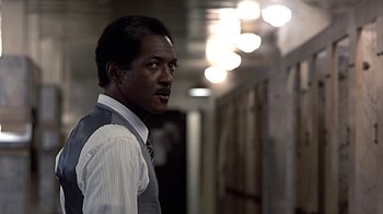 Movie still from “Beverly Hills Cop” (1984), directed by Martin Brest – A man wearing a suit and tie standing in a hallway; Close Up shot, Low angle