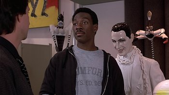 Movie still from “Beverly Hills Cop” (1984), directed by Martin Brest – A man standing in front of a statue of himself; Medium shot, Over the shoulder angle